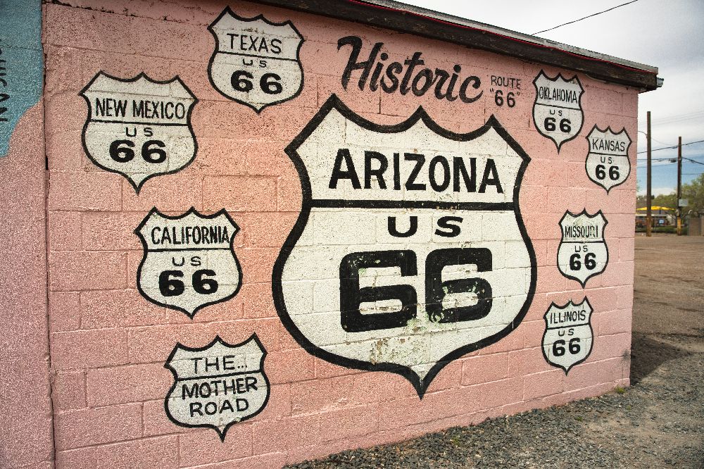 A vintage pink car parked in front of a historic Route 66 motel