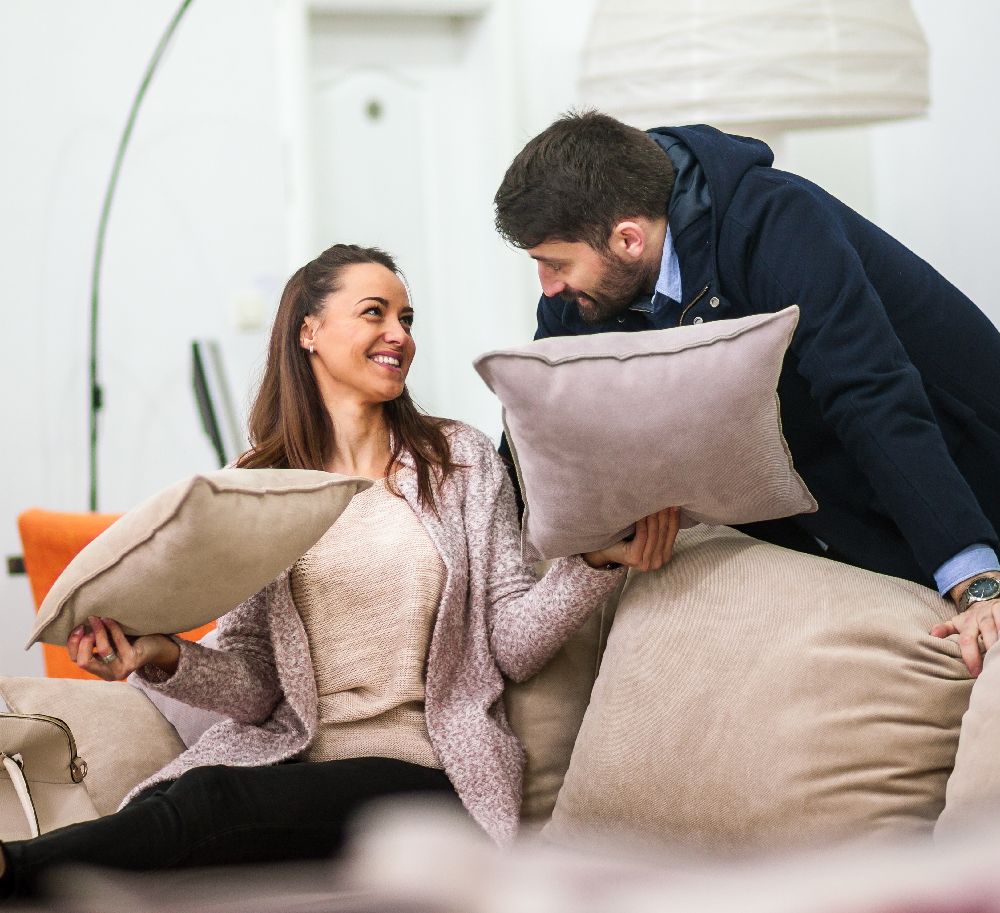 A stylish accent pillow and throw blanket on a sofa, representing flexible and affordable decor