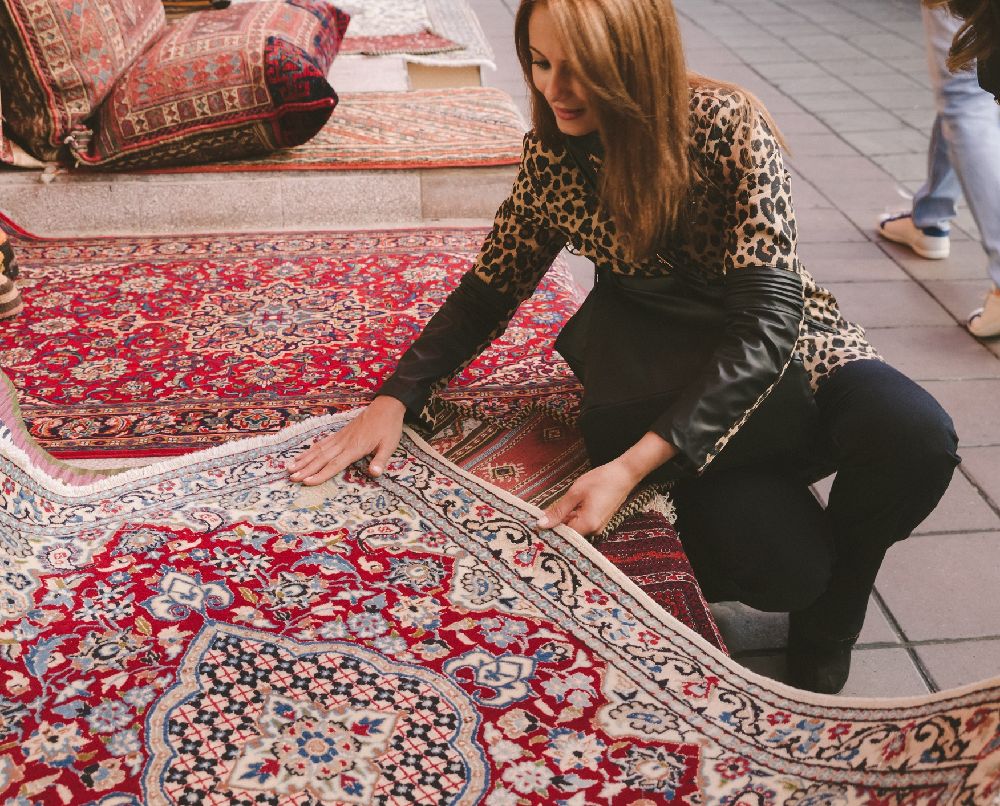 A person feeling the texture of a rug while shopping