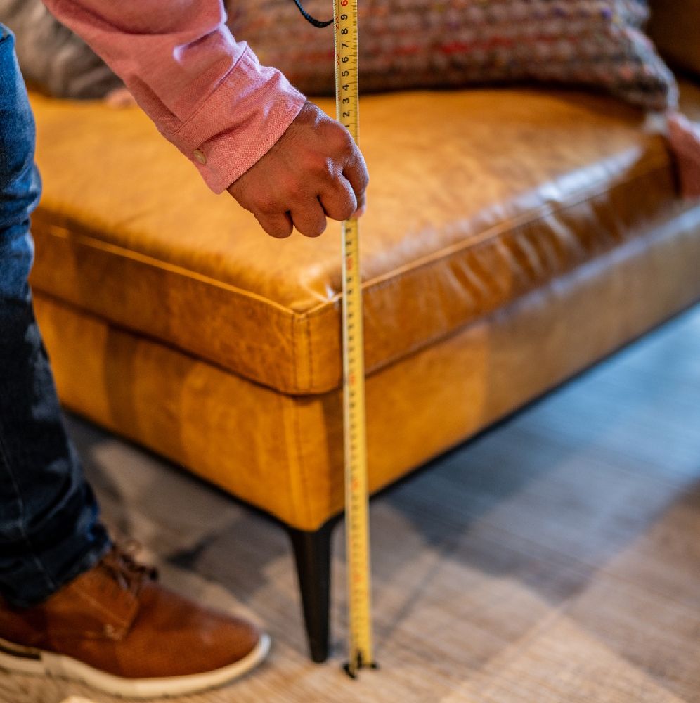 A person considering the scale and proportions of a sofa in a living room